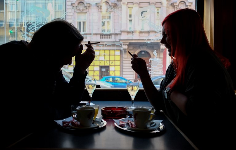 Guests of a Vienna's Cafe/Bar smoke cigarettes with their drinks in Vaienna, Austria, on March 22, 2018. Austrian parliament has announced today that a planned ban on smoking in all bars and restaurants that was due to come into force in May of 2018 will be scrapped. / AFP PHOTO / JOE KLAMAR